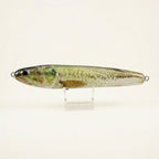 Largemouth bass pattern JigSkinz lure skin on a stickbait, displayed on clear stand against dark background