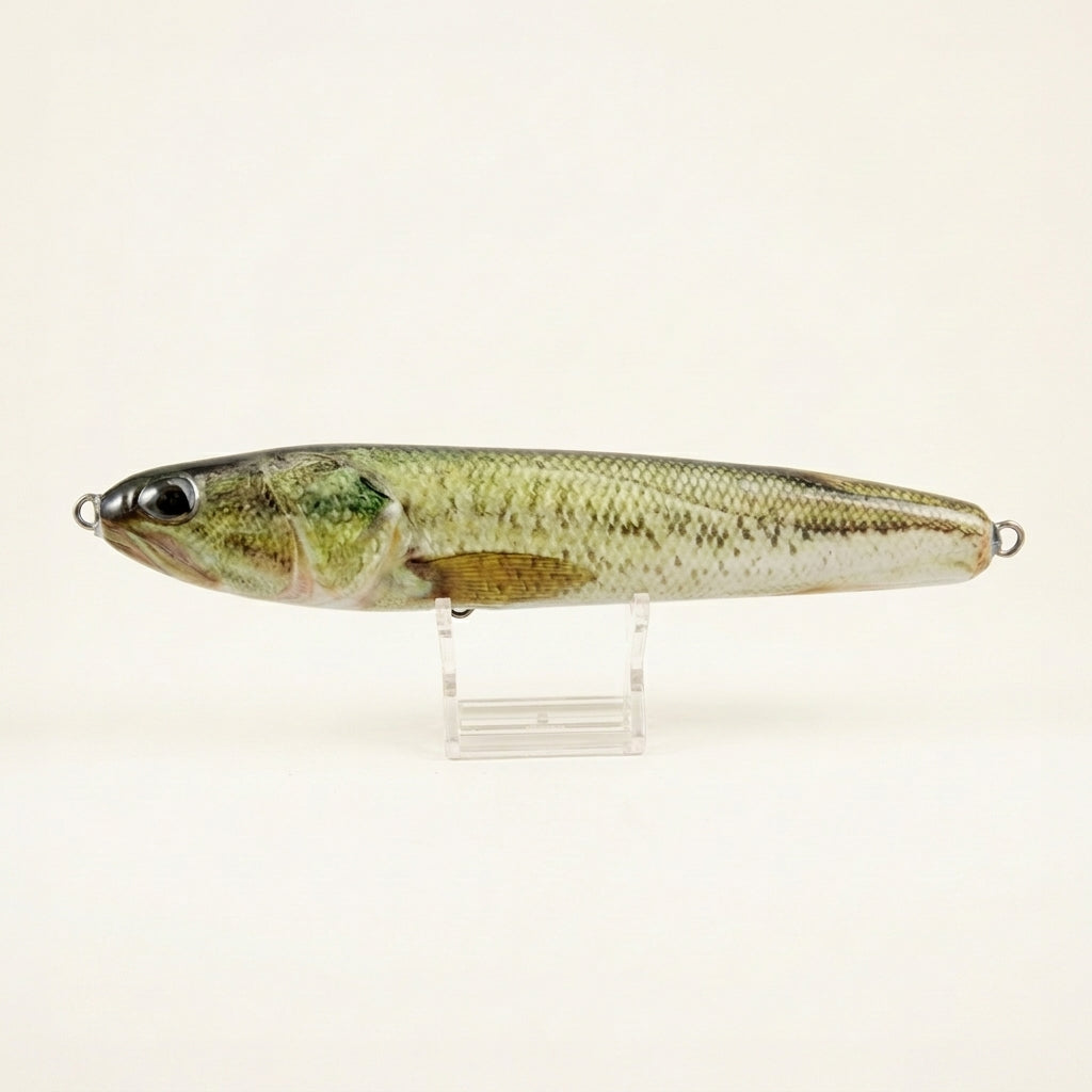 Largemouth bass pattern JigSkinz lure skin on a stickbait, displayed on clear stand against dark background