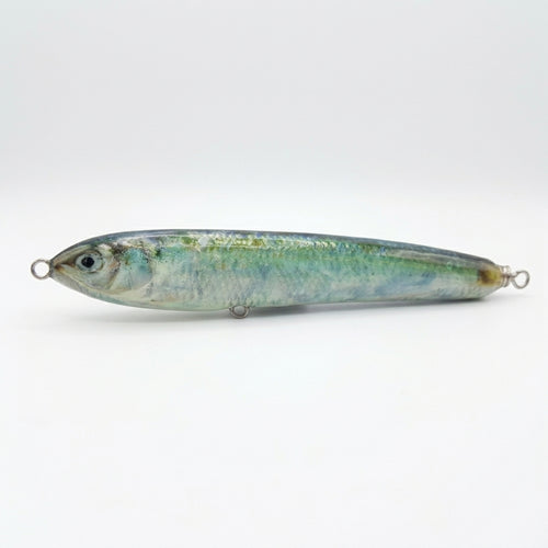 Blueback herring pattern JigSkinz lure skin on a topwater stickbait, side view on dark countertop