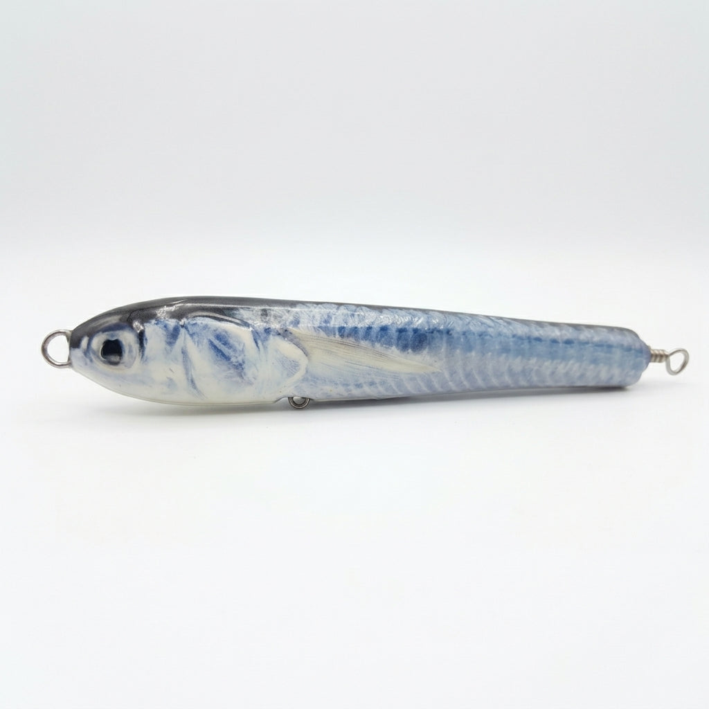 Ballyhoo pattern JigSkinz lure skin on a saltwater pencil popper, side view on dark background