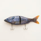 Pond bluegill pattern JigSkinz lure skin on a jointed swimbait with treble hooks, on dark granite