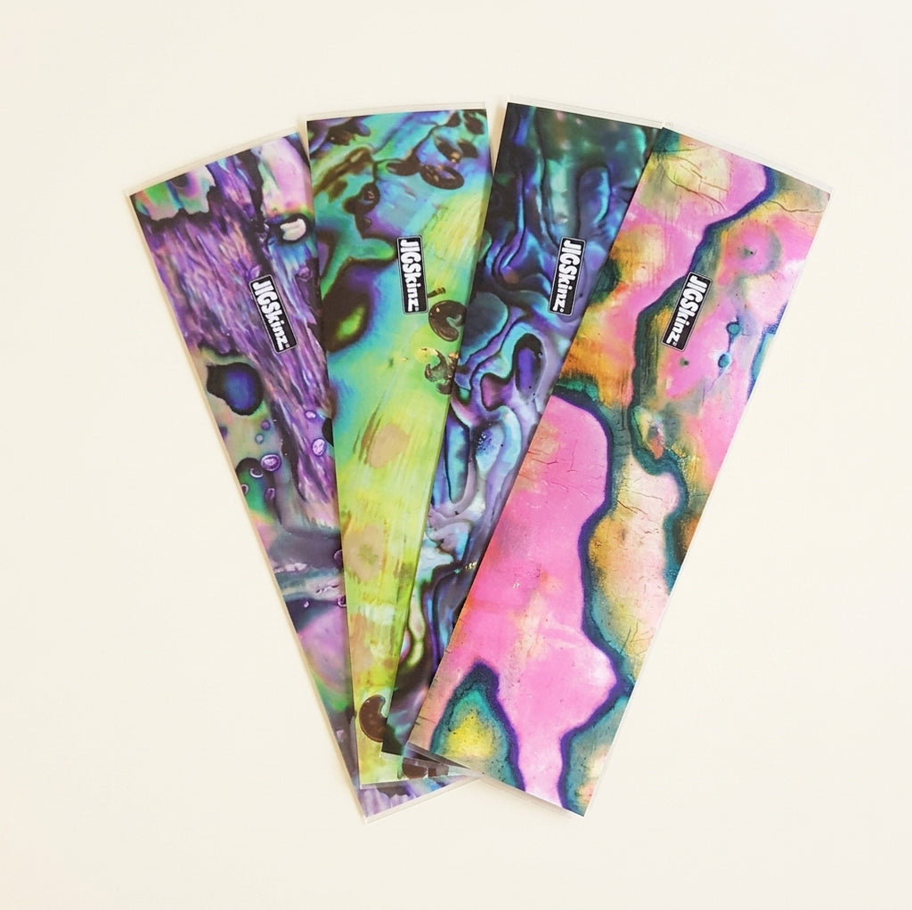 JigSkinz abalone lure skin sheets fanned out in four shell color patterns on dark granite
