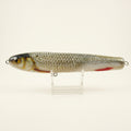 Roach pattern JigSkinz lure skin on a stickbait, on clear stand outdoors with green foliage behind